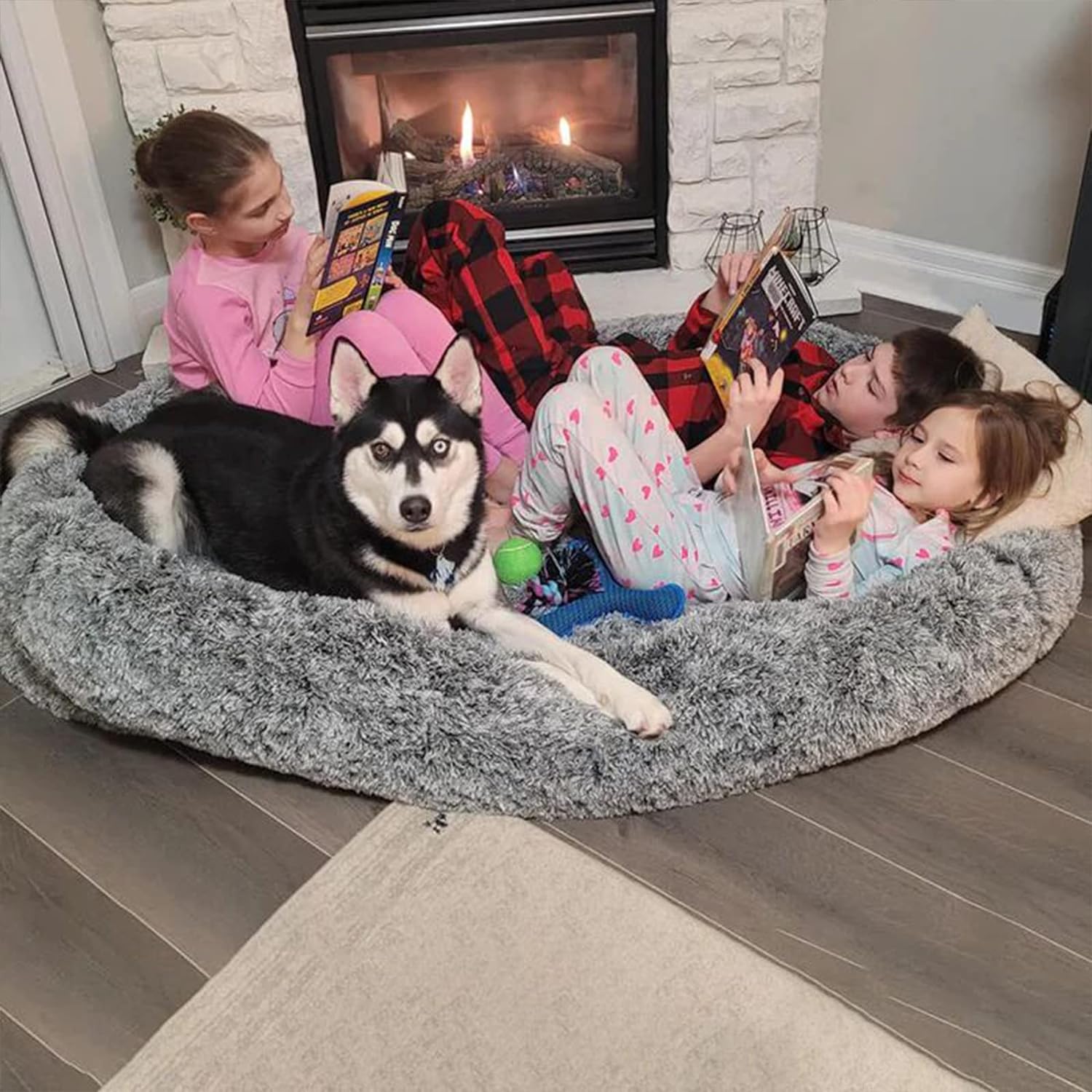 "A happy family sitting together in front of a cozy fireplace, their dog snuggled up with them."