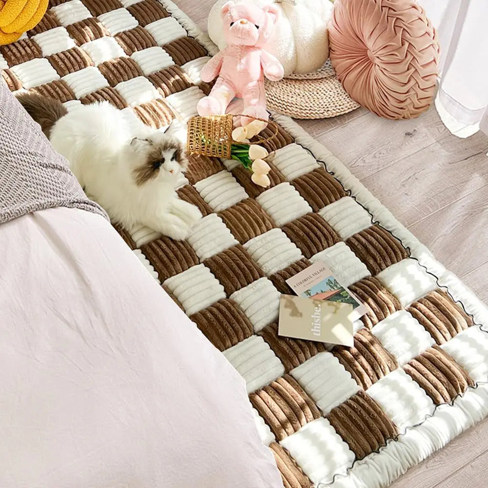 "One cat resting on a brown checkered quilted couch cover."
