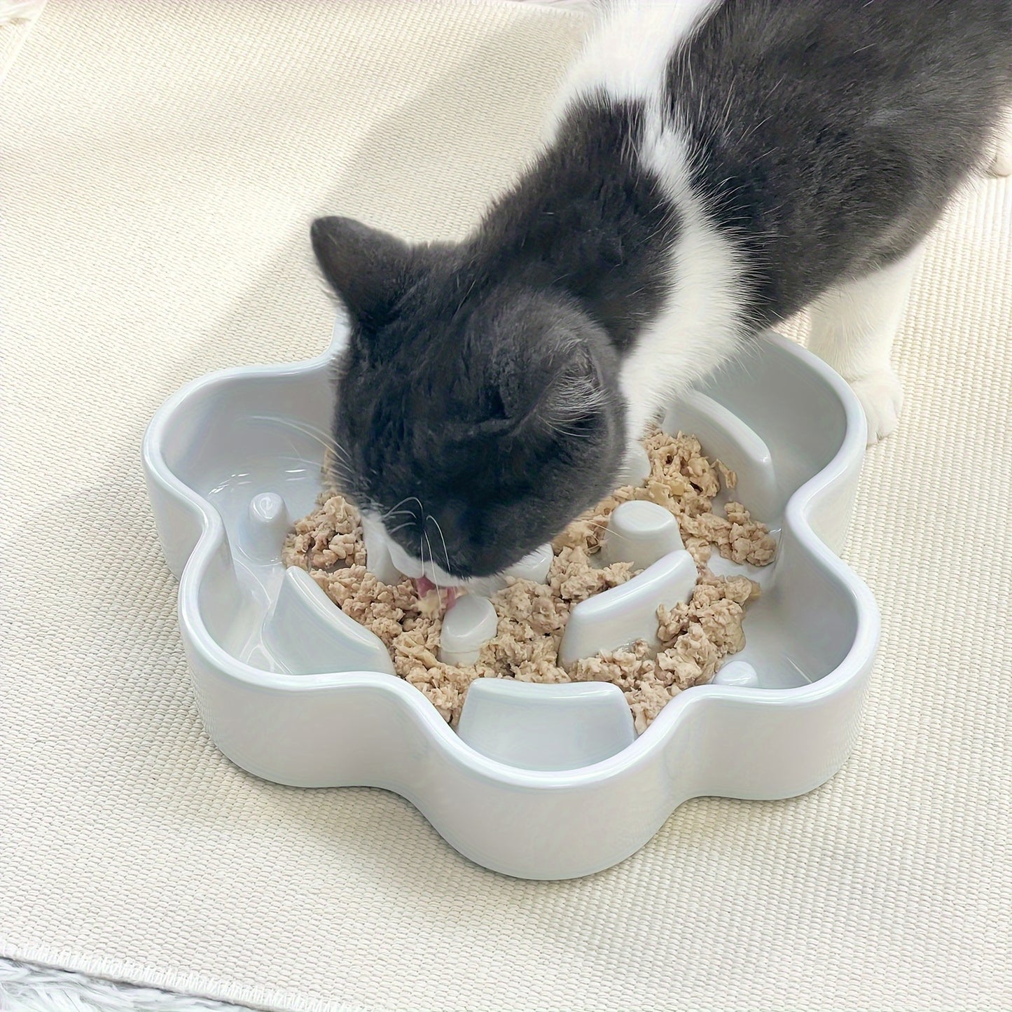 A cat using the Paw Shaped Ceramic Slow Feeder