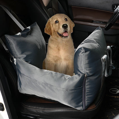 "Golden Retriever lying in a grey travel bolster bed in the car."
