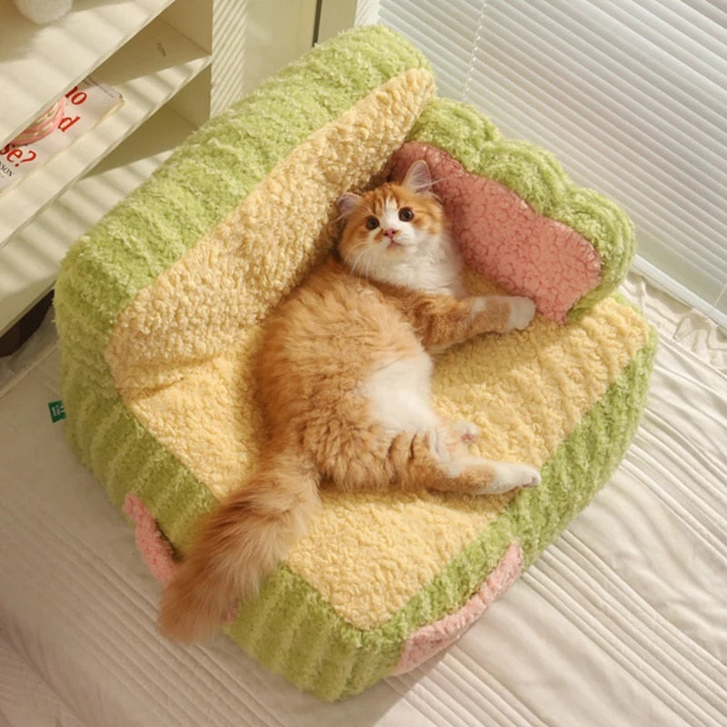 "Ginger cat lying on a green super soft sherpa fleece pet sofa, looking directly at the camera."
