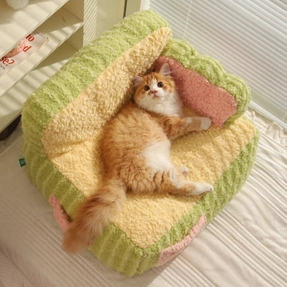 "Ginger cat lying on a green super soft sherpa fleece pet sofa, looking directly at the camera."
