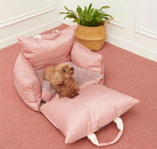 "Small dog resting in a pink fold-out travel bolster bed."
