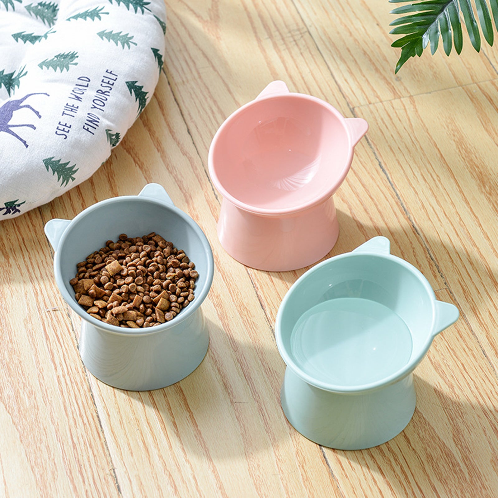 "Three ergonomic cat feeding bowls in different colors, one filled with food.